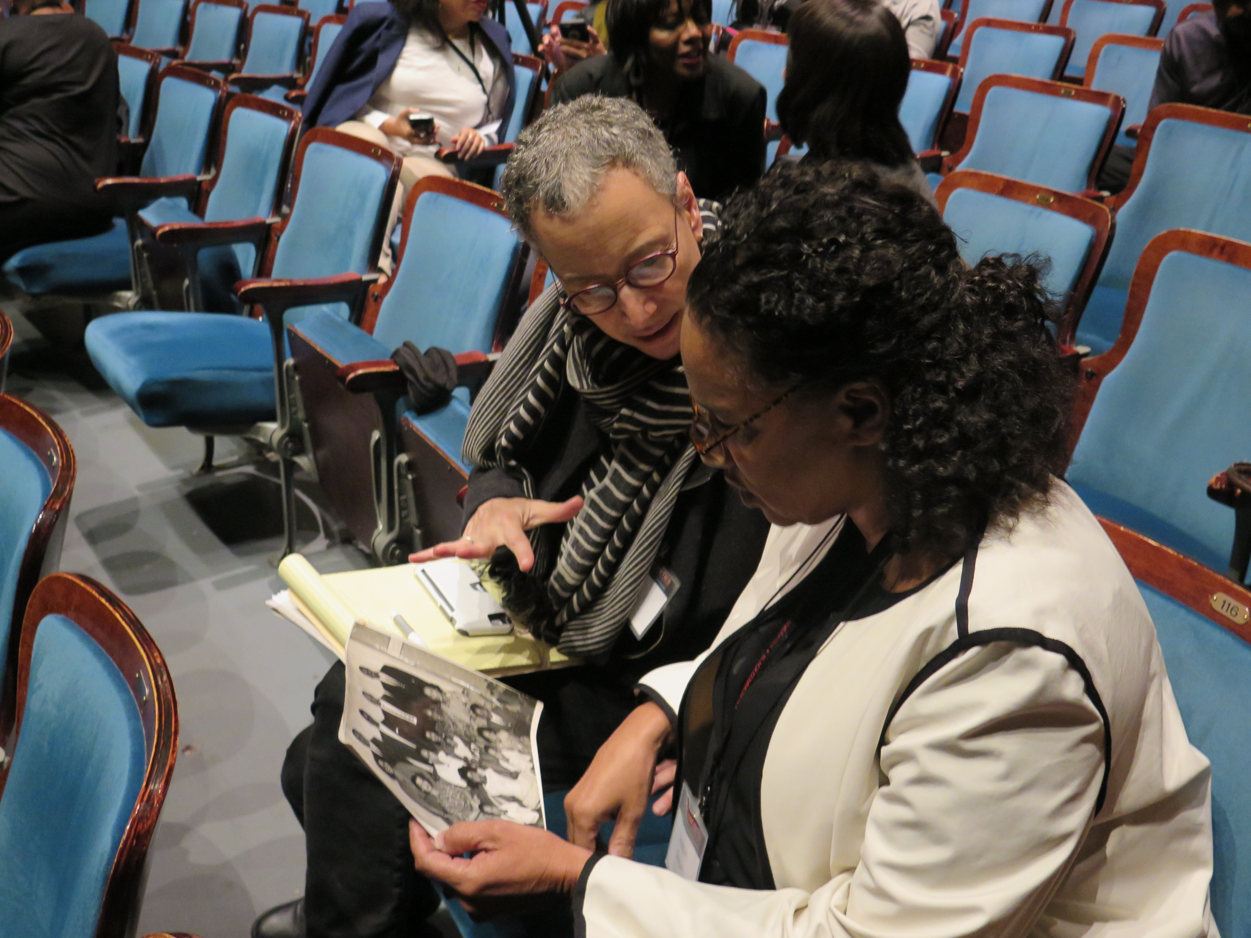 Two participants examine a photo at the Black Communities Conference